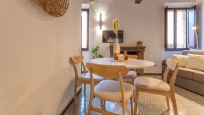 Een gezellige woonkamer met een ronde eettafel, houten stoelen, een bank en een open haard.