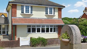 A two-story house with a white facade, a brick base, and a tiled roof. - 4 bedroom accommodation in Freshwater (Freshwater)