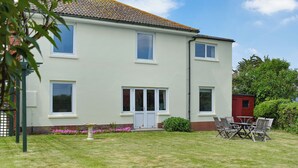 A two-story house with a front garden, a patio with chairs, and a small shed. - 4 bedroom accommodation in Freshwater (Freshwater)