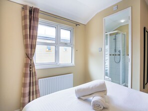 Une chambre d’hôtel avec un lit, une fenêtre avec des rideaux, un radiateur et un espace douche.