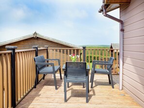 A wooden deck with outdoor furniture, a view of the countryside, and a wooden building.