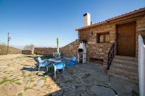 A stone building with a wooden door, a stone staircase, and a patio with chairs and a table. - Holiday Home 'Casa Rural Jaraiz Vip' with Mountain View, Shared Pool and Wi-Fi (Laroya)