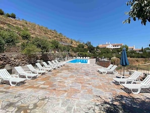 A pool area with stone flooring, white lounge chairs, and a clear blue sky. - Holiday Home 'Casa Rural Jaraiz Vip' with Mountain View, Shared Pool and Wi-Fi (Laroya)