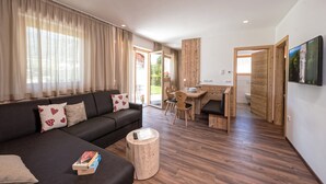 Una sala moderna con sofá, una mesa de centro y un comedor con mesa y sillas de madera.