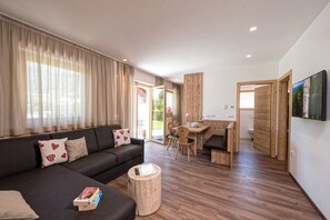 Ein modernes Wohnzimmer mit einer Couch, einem Couchtisch und einem Essbereich mit einem Holztisch und Stühlen.