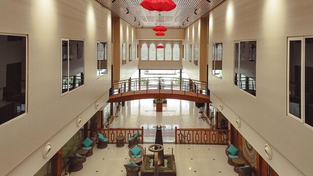 Un hall d’entrée spacieux avec un escalier central, de nombreux espaces de détente et de grandes fenêtres.