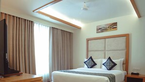 Une chambre d’hôtel avec un grand lit, un téléviseur posé sur un meuble en bois et un tableau accroché au mur.
