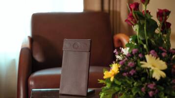 Una silla de cuero marrón con un teléfono inteligente en una funda de cuero sobre una mesa de vidrio.