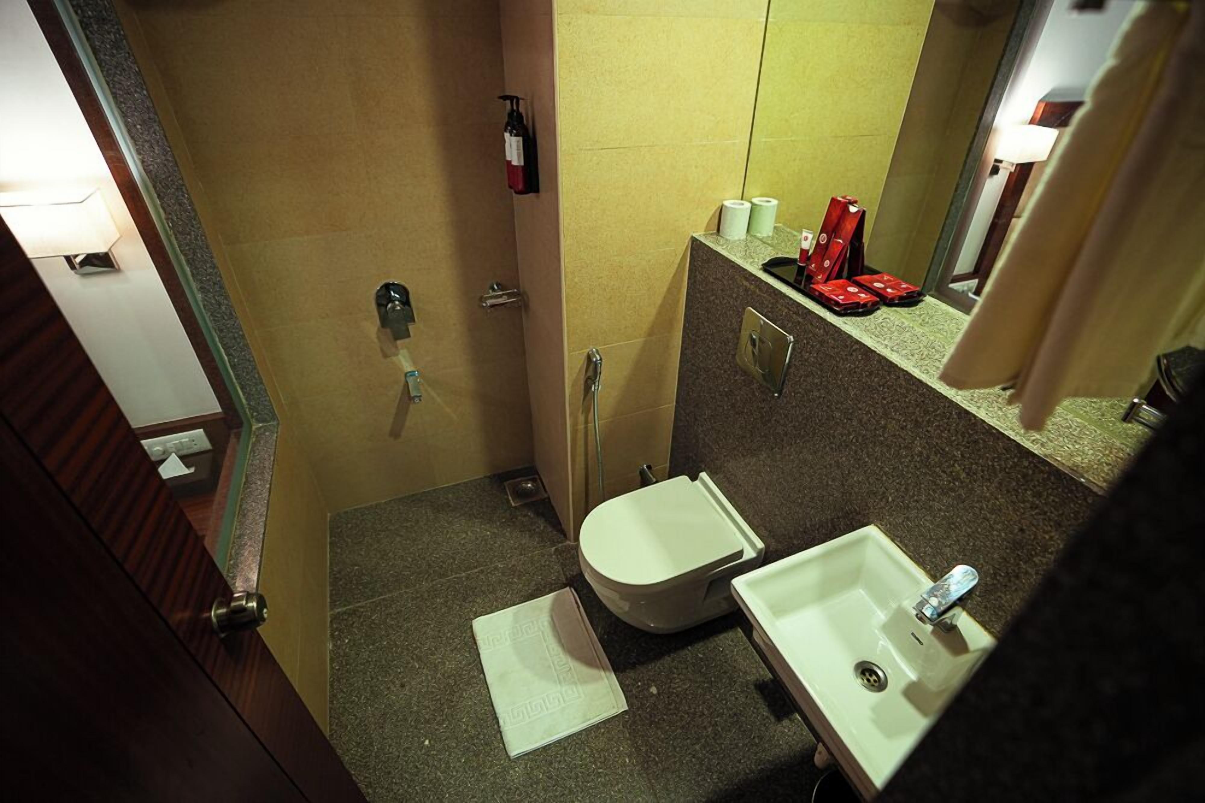 A small bathroom with a toilet, sink, and a mirror.