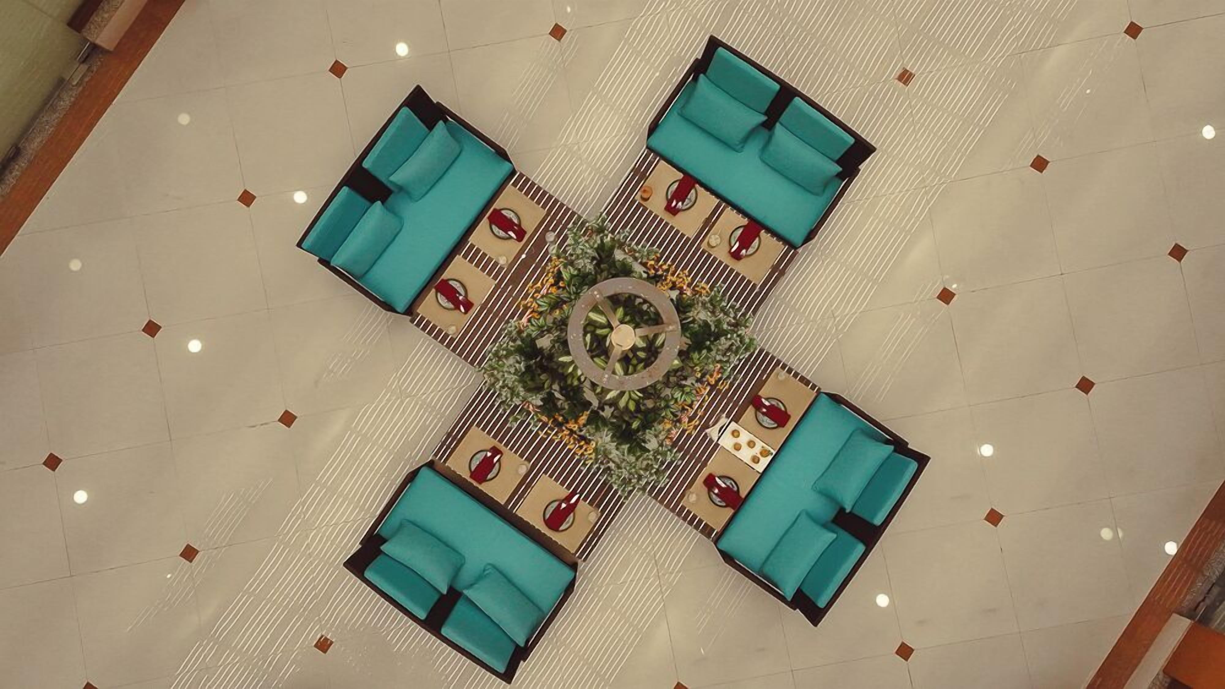 A top-down view of a dining area with a central circular table surrounded by four blue cushioned seating areas.