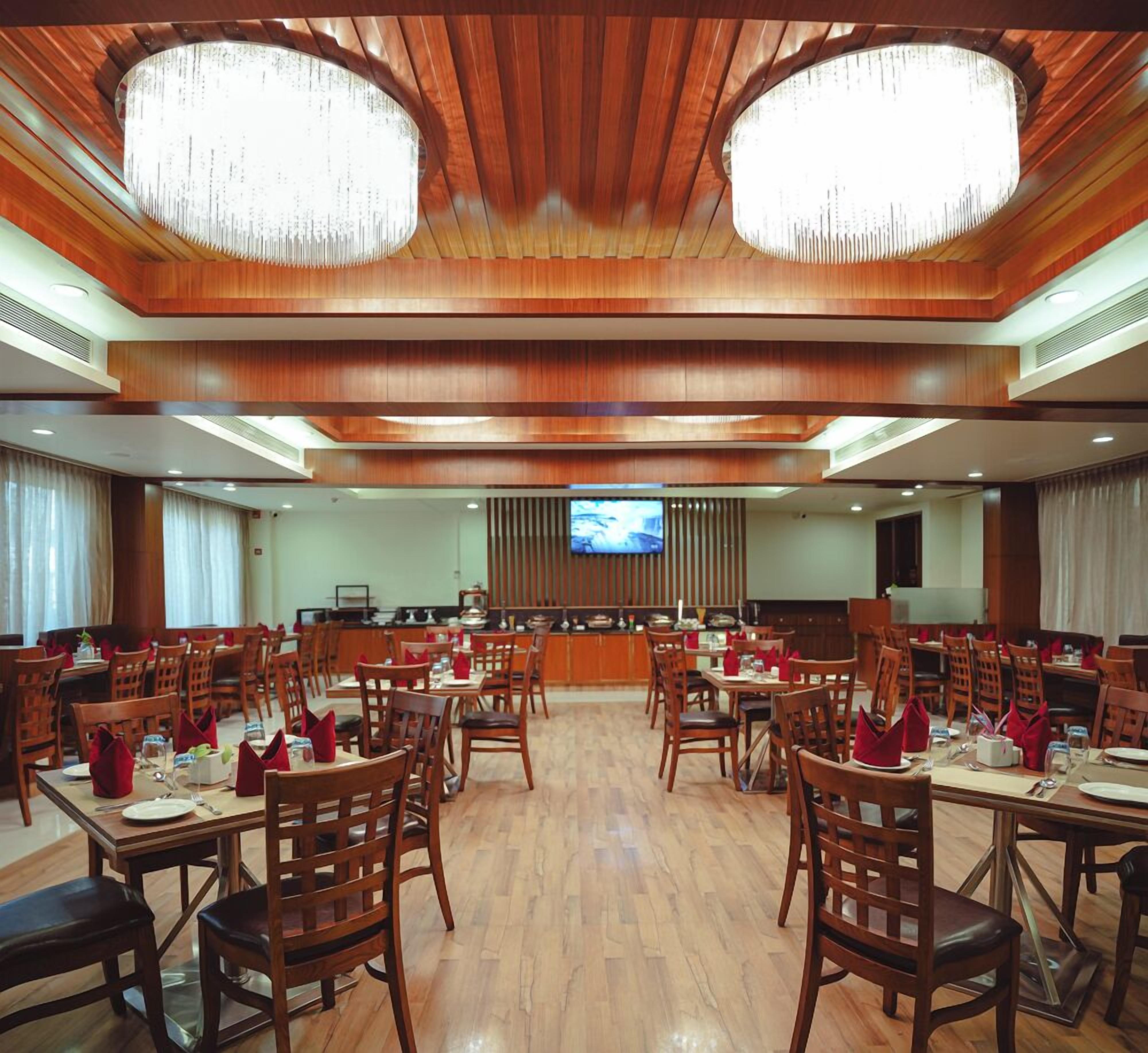 A large dining area with wooden tables and chairs, a central counter, and a television screen.