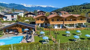 A hotel with a pool, outdoor seating, and mountain views.