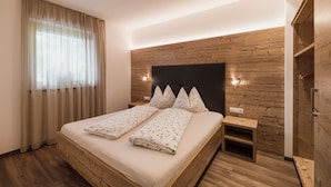 A bedroom with a wooden headboard, a bed with floral bedding, a nightstand, and a built-in wooden wardrobe.