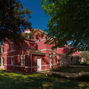 A red building with white trim, a stone entrance, and a well-maintained lawn.