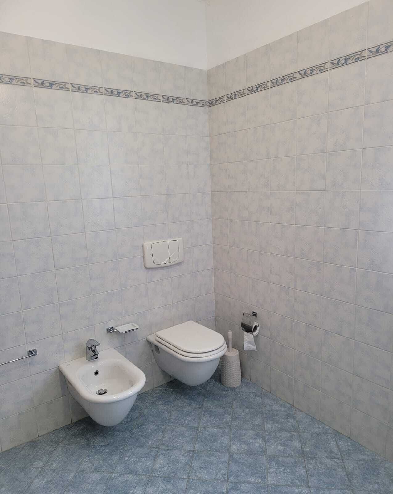 Ein Badezimmer mit einem Bidet, einer Toilette und einem Handtuchhalter.