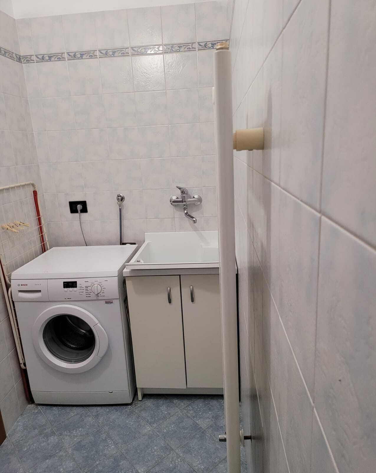 A compact laundry room with a Bosch washing machine, a sink, and cabinets.