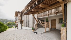 Une maison moderne dotée d’un balcon en bois, d’un escalier et d’une allée pavée.