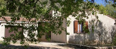 A rustic building with a stone foundation, a tiled roof, and a window with wooden shutters.
