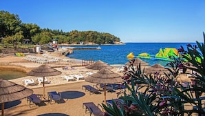 A beach with sun loungers, umbrellas, and a lifeguard tower.