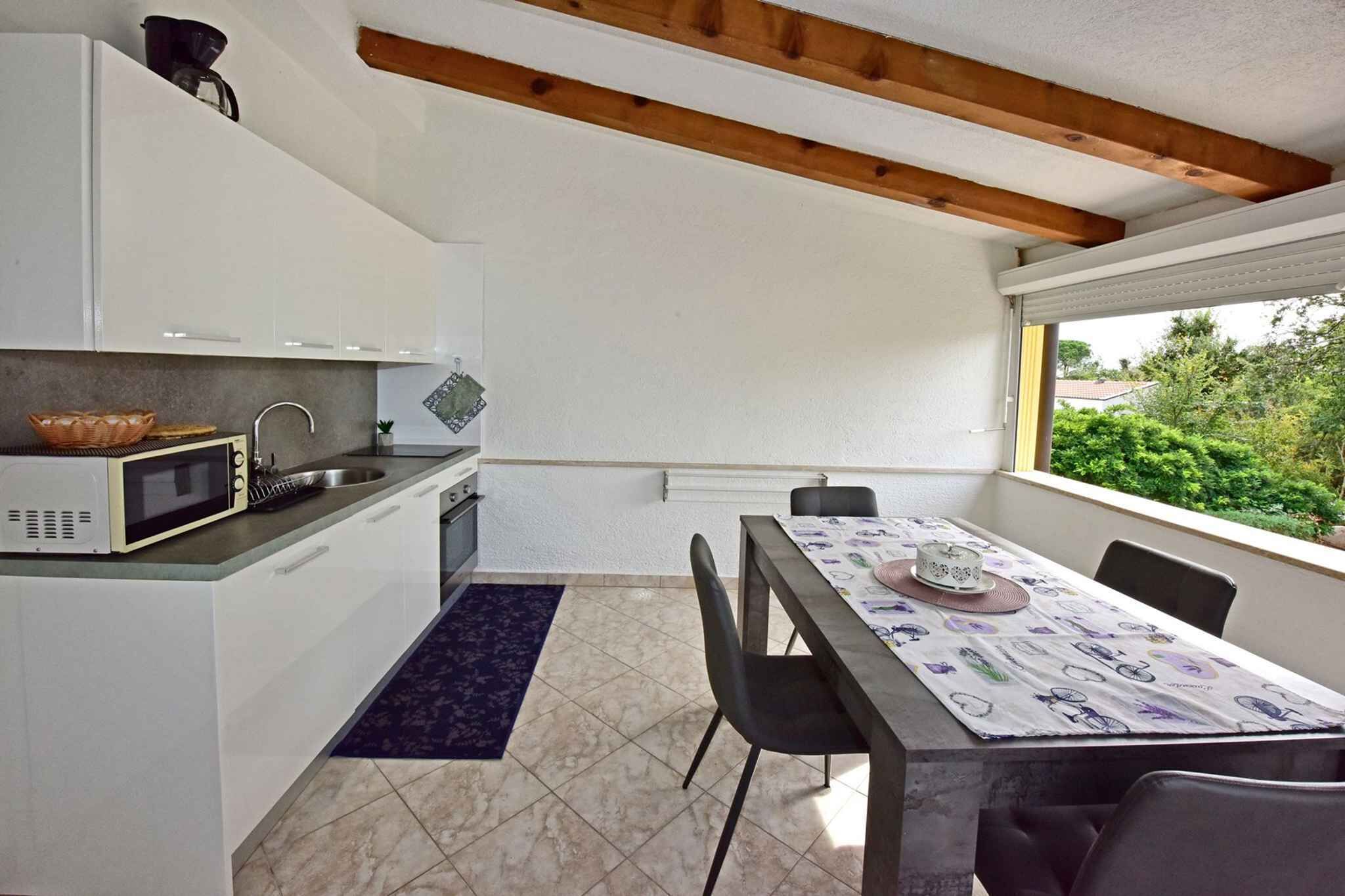 Une cuisine compacte avec des meubles blancs, un four à micro-ondes et un coin repas comprenant une table et des chaises.