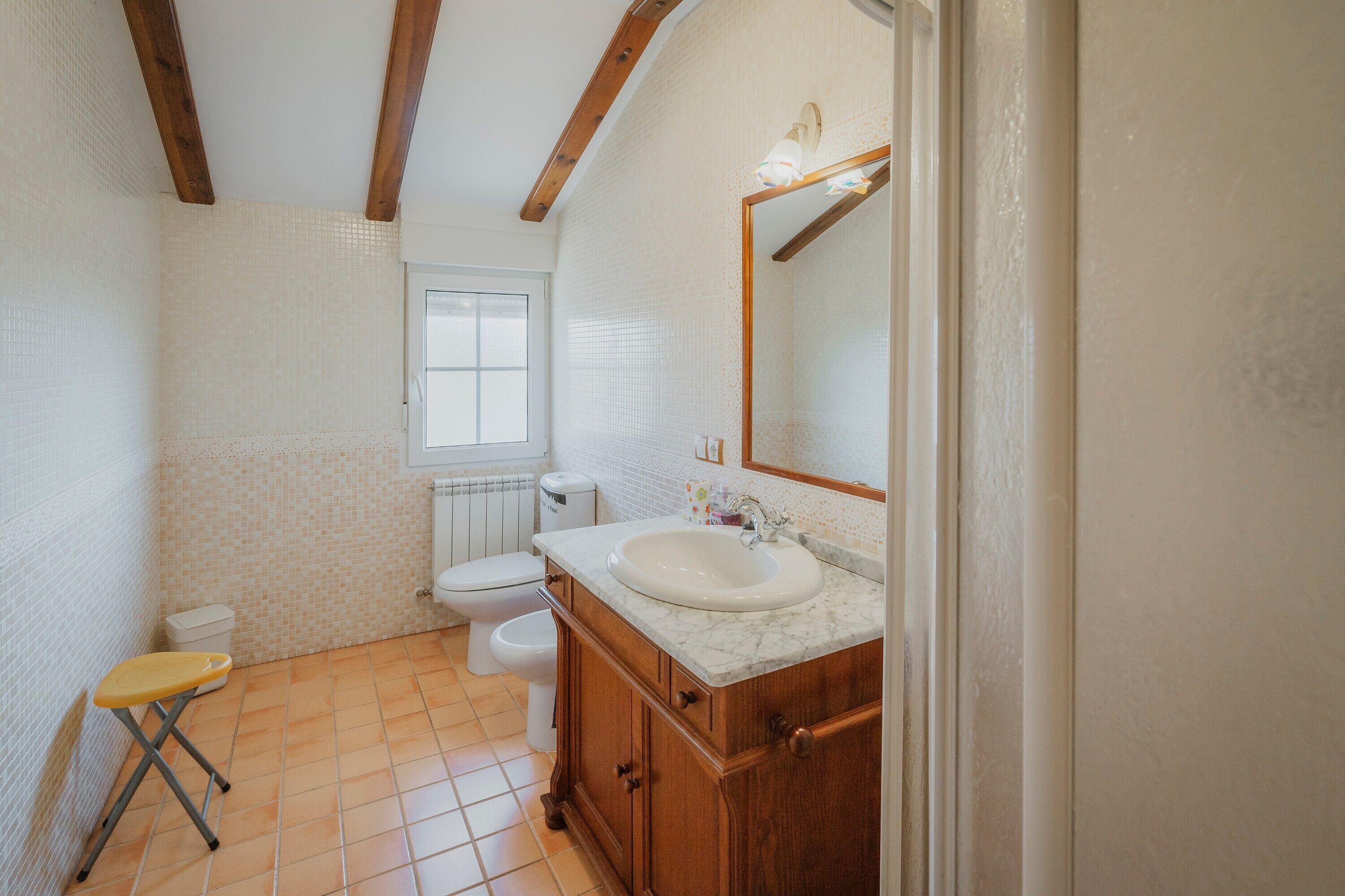 Un bagno con il water, un lavandino, un mobile bagno in legno e uno specchio.