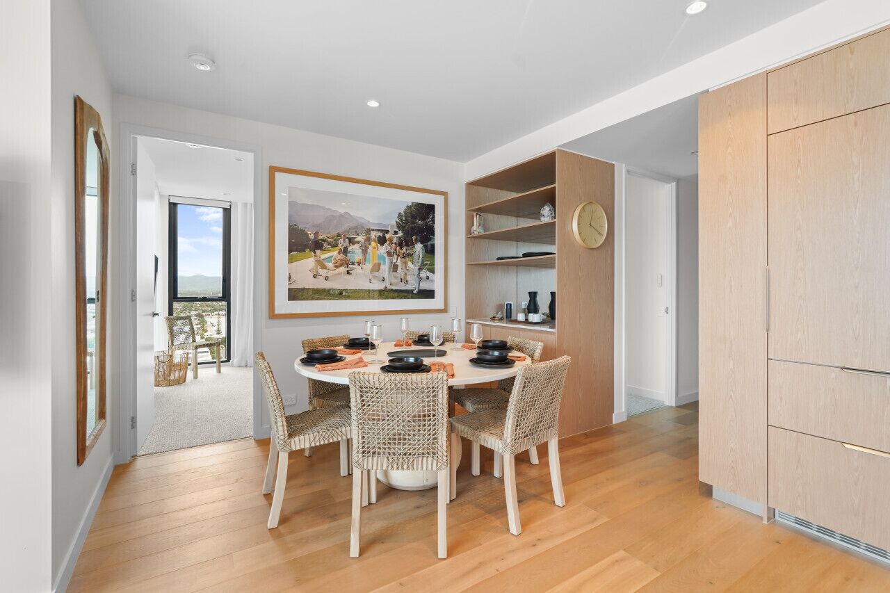 Un coin repas avec une table ronde, des chaises en osier et un tableau accroché au mur.