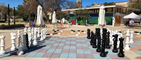 Un tablero de ajedrez grande al aire libre instalado en una plaza pública con un edificio al fondo.