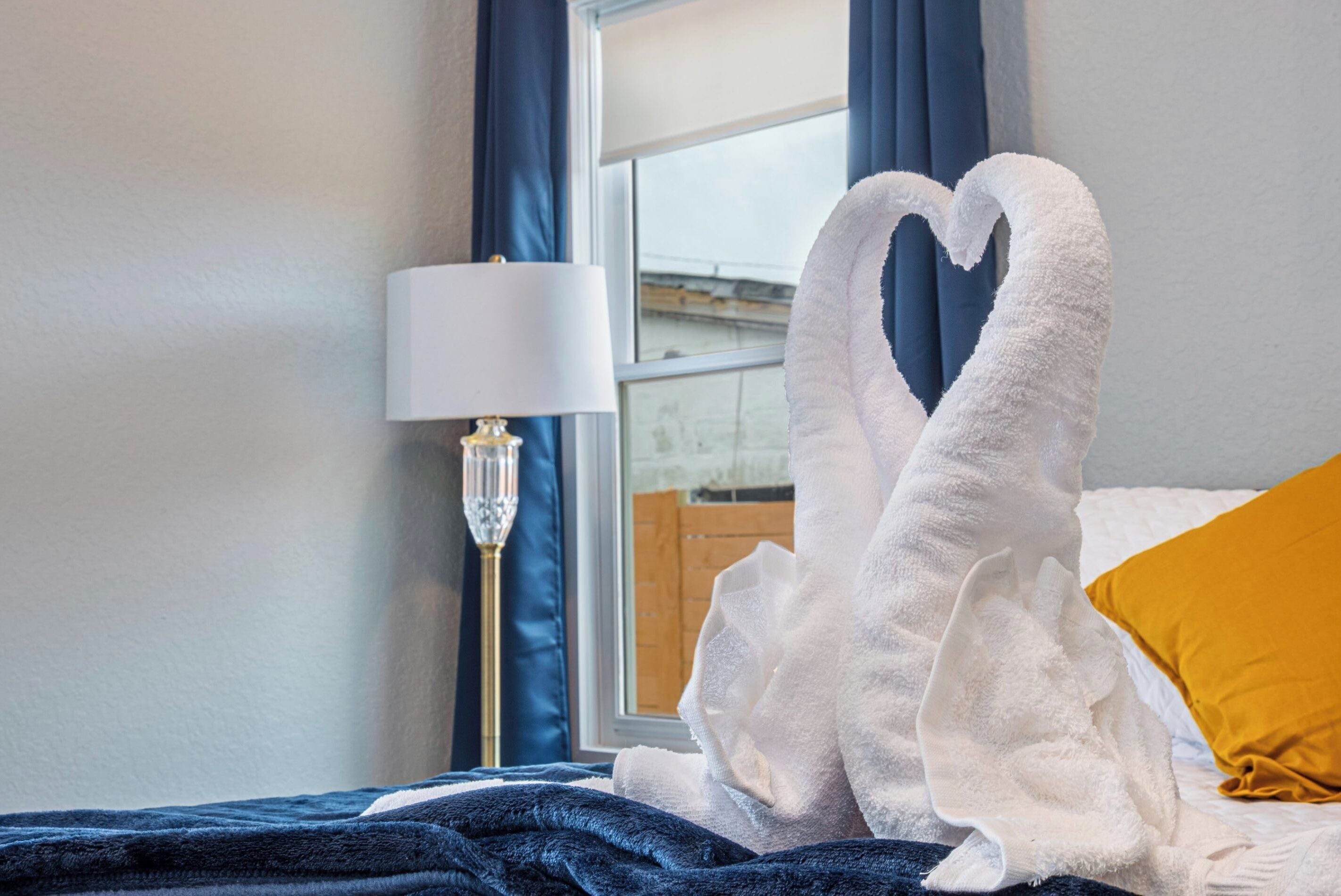 Une chambre d’hôtel avec un lit, une lampe et une fenêtre avec des rideaux.