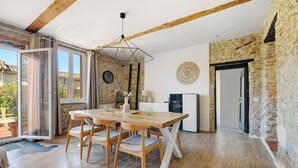 A dining area with a wooden table and chairs, a hanging light fixture, and a stone wall. - Holiday Home 'Villa Avec Piscine Soupex' with Private Pool, Private Terrace and Wi-Fi (Soupex)