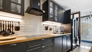 A modern kitchen with dark cabinetry, a stainless steel refrigerator, and a wooden countertop. - Holiday Home 'Villa Avec Piscine Soupex' with Private Pool, Private Terrace and Wi-Fi (Soupex)