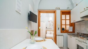 A compact kitchen with white cabinets, a stove, and a dining area with a table set for two.