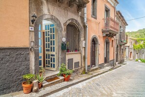 Un bâtiment historique doté d’une façade en pierre, de fenêtres en arc de cercle et bordé d’une rue pavée.