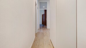 A narrow hallway with wooden flooring and white walls.