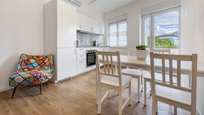 A modern kitchen with white cabinets, a tiled backsplash, and a window with a view.
