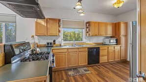 A modern kitchen with wooden cabinets, stainless steel appliances, and a large window. - Sterling Hideout on the Kenai Peninsula (Sterling)