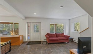 A spacious living area with a red sofa, a television, and a fireplace. - Sterling Hideout on the Kenai Peninsula (Sterling)