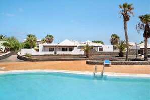 A resort with a swimming pool, white buildings, and palm trees.