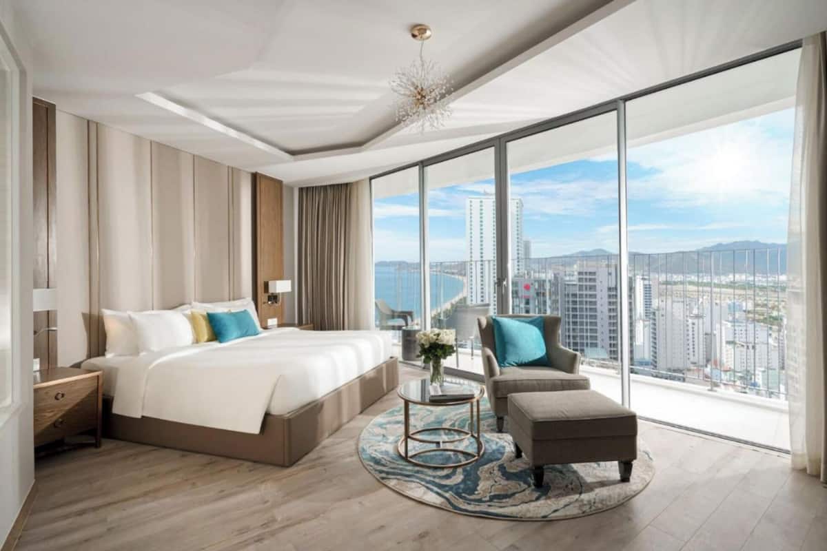 Een moderne hotelkamer met een groot bed, een slaapbank en uitzicht op de stad.