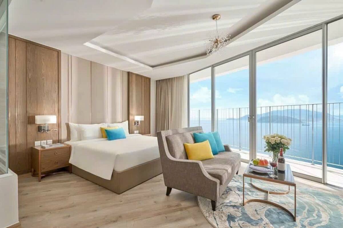 Een moderne hotelkamer met een groot bed, een bank en een balkon met uitzicht.