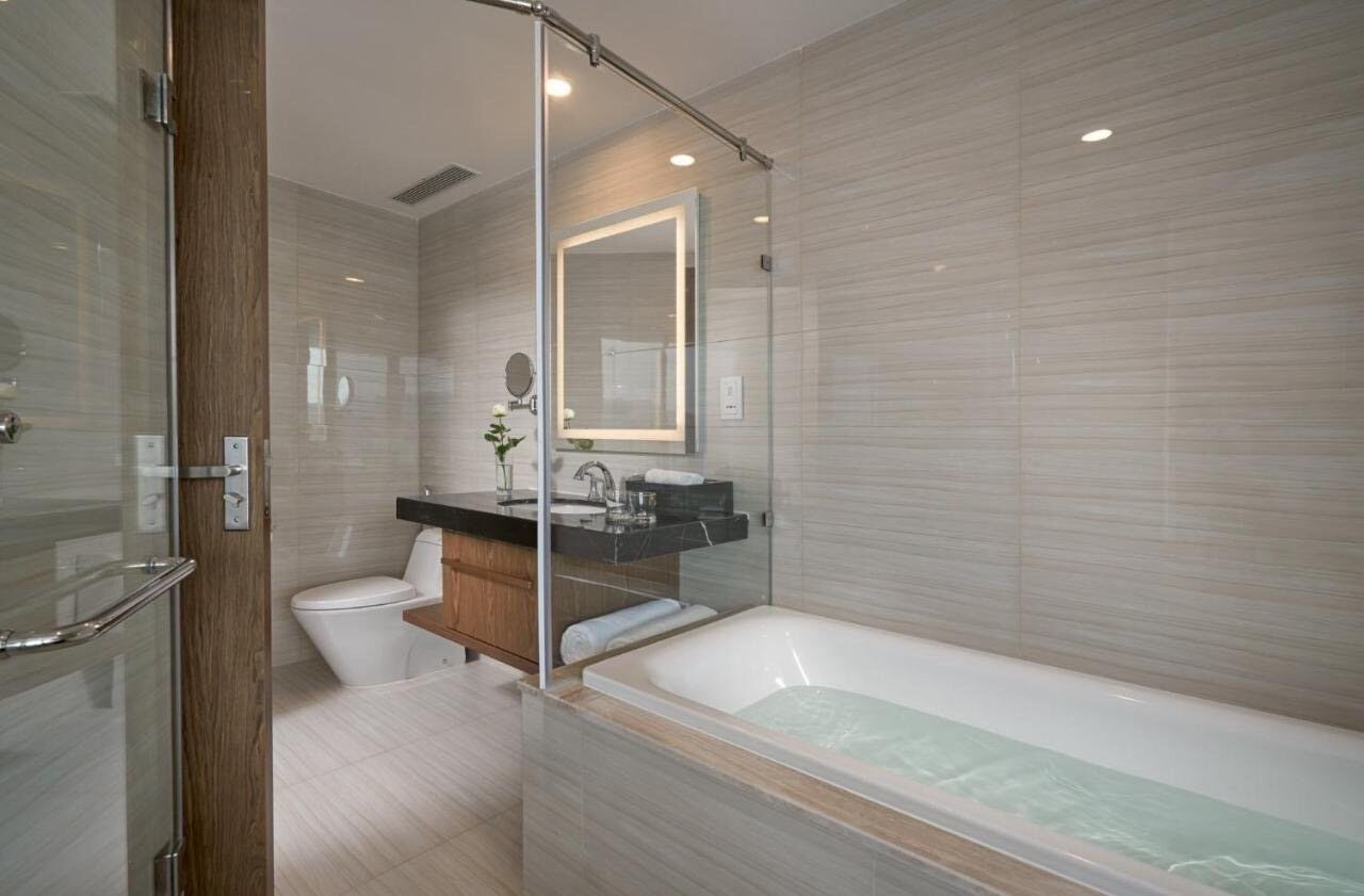 A modern bathroom with a glass shower enclosure, a freestanding bathtub, a toilet, and a vanity with a mirror.