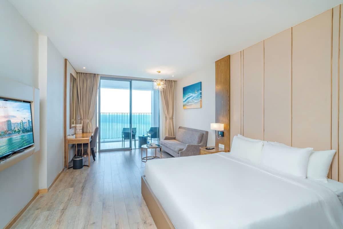 Een hotelkamer met een groot bed, een bureau, een stoel, een televisie en een balkon met uitzicht.