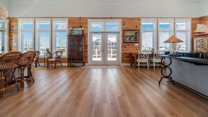 A spacious kitchen with wooden floors, large windows, and a view of the city. - Sea Salt Cottage with private boat dock (Atlantic Beach)