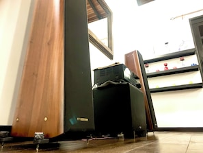 Une pièce avec un plancher en bois, un haut-parleur noir et une étagère contenant des objets rouges et verts.