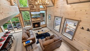 A cozy cabin interior with a fireplace, wooden furniture, and large windows offering views of the outdoors. - 3 levels of Luxury*Modern*Private Pool*Stunning Views (SEVIERVILLE)