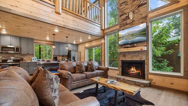 A spacious living area with a fireplace, leather sofa, and large windows offering a view of the outdoors. - 3 levels of Luxury*Modern*Private Pool*Stunning Views (SEVIERVILLE)