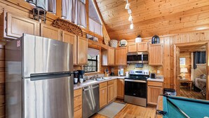 A modern kitchen with wooden cabinets, stainless steel appliances, and a pool table. - Near Dollywood*Easy Access Roads*Jacuzzi*Pool Table (SEVIERVILLE)