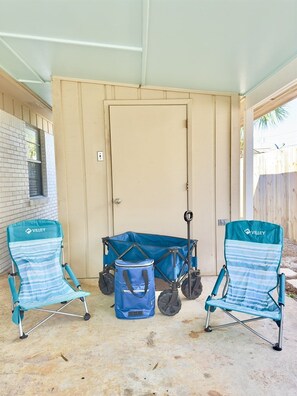 Un patio couvert avec deux chaises pliantes bleues et un chariot utilitaire bleu.