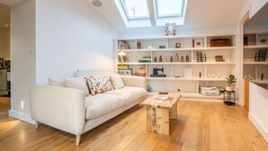 Een moderne woonkamer met een witte bank, een houten salontafel en een inbouwboekenplank.