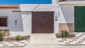 Edifici amb una porta marró tancada, entrada enrajolada i una petita zona de jardí.