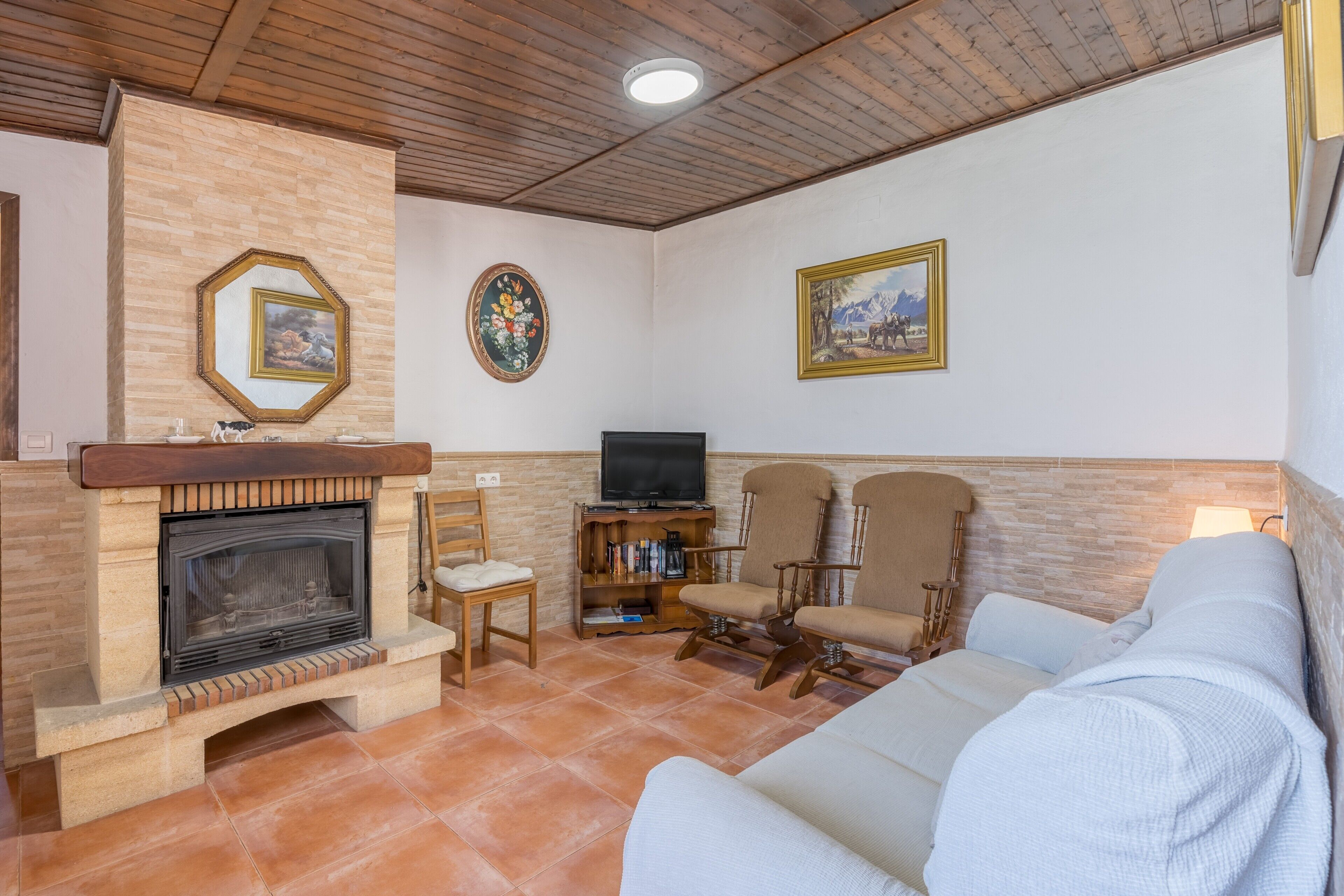 A living room with a fireplace, a television, a sofa, and two armchairs.